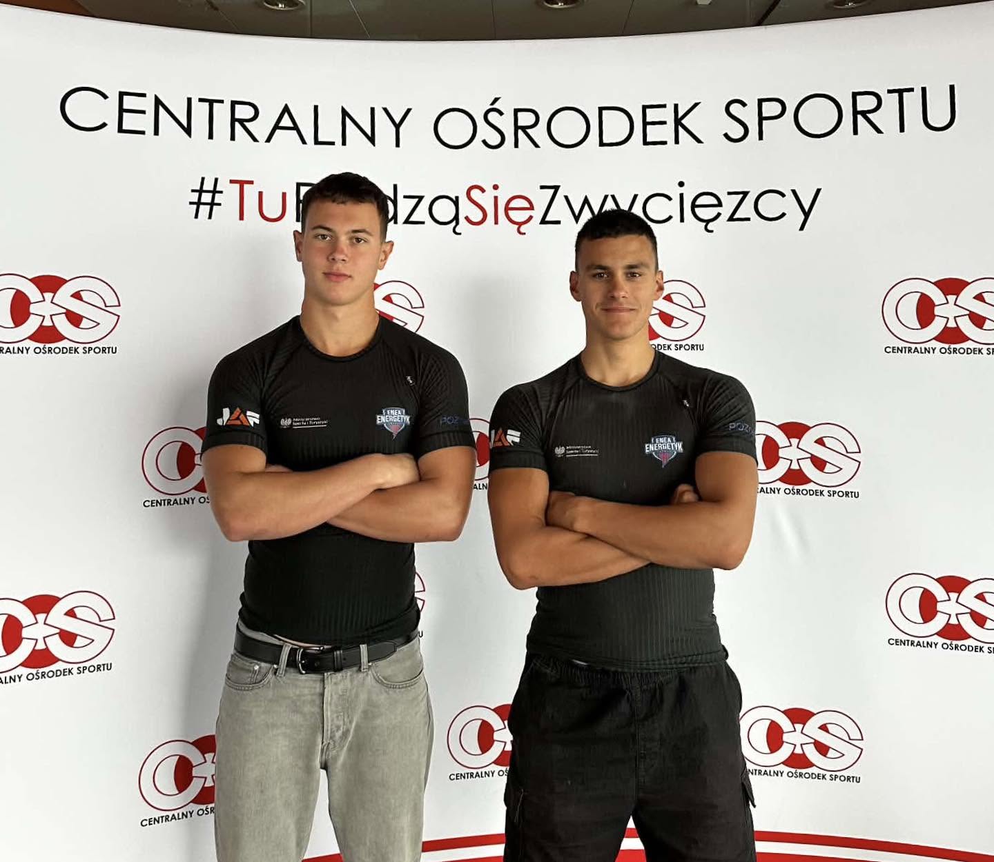 Kajakarze w strojach reprezentacyjnych stojący nad wodą